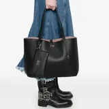 Cartera tipo tote Guess modelo Brenton, color negro con textura granulada. Incluye un sobre pequeño desmontable y un neceser interior a juego, ambos con logo de la marca en letras metálicas doradas.