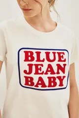 Remera de algodón blanca con cuello redondo y estampa frontal con el texto 'BLUE JEAN BABY' enmarcado en un recuadro negro.