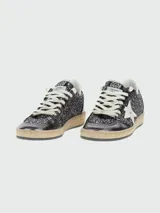 Zapatillas Golden Goose modelo Ballstar, caña baja, con capellada y lengüeta de glitter negro/plateado. Presentan puntera laminada oscura y estrella lateral blanca. La suela es de goma con efecto desgastado.