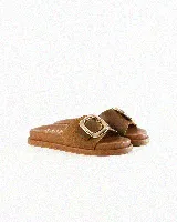 Sandalias de cuero color negro, de diseño plano con una tira ancha en el empeine y una hebilla metálica dorada grande como detalle.