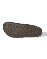 Zuecos de estilo mule marca Rivaro, confeccionados en cuero gamuzado color marrón moca. Presentan una tira ajustable con hebilla metálica grabada con el logo de la marca y una suela anatómica de corcho y látex.
