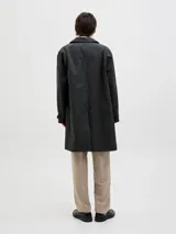 Campera tipo trench liviana de corte recto y largo medio, color negro, con cuello camisero, cierre frontal de botones y puños ajustables con trabilla.