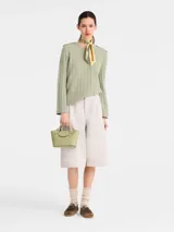 Cartera tipo tote en tamaño extra pequeño, confeccionada en cuero liso color verde oliva. Presenta una estructura rígida, doble asa corta superior y cierre con solapa y broche metálico con logo grabado.
