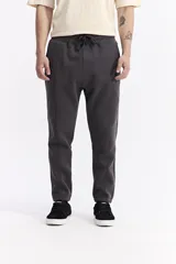 Pantalón de jogging negro de algodón y poliéster, con puños ajustados en los tobillos, cintura elástica con cordón y costuras verticales marcadas en el frente.