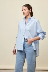 Camisa celeste de corte oversize, con mangas largas, cuello camisero y cierre frontal de botones.