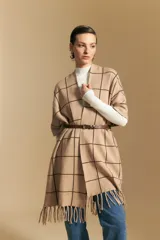 Poncho abierto de tejido de punto con diseño de cuadros grandes en contraste. Presenta un patrón reversible en tonos negro y marrón, con un estilo envolvente y versátil.