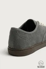 Zapatilla deportiva barefoot fabricada en piel con acabado serraje de color marrón, con cordones en contraste y suela fina de goma.