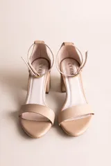 Sandalias de cuero color tostado con tira frontal ancha, taco ancho de altura media y tira con hebilla alrededor del tobillo.