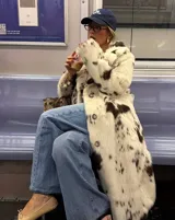 Tapado midi de piel sintética con estampado de manchas tipo vaca en tonos blanco y marrón. Presenta cuello amplio, cierre frontal con botones y corte recto de ajuste relajado.