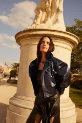 Campera de cuero azul metalizado, de corte oversize, con solapas amplias y forro interior de corderito, mangas abullonadas y detalle de costuras trenzadas en el frente.