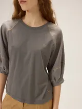 Remera de algodón con escote a la base y mangas raglán de broderie con costuras decorativas en color contrastante.