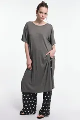 Vestido midi color beige, de corte oversized, con cuello redondo, manga corta y tajos laterales. Presenta un parche decorativo en la manga.