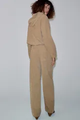 Pantalón de tiro medio color beige, de pierna ancha y corte recto. Cuenta con cintura elástica ajustable con cordones y bolsillos frontales.