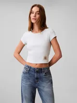 Remera Calvin Klein de manga corta y corte crop top, confeccionada en tejido de punto acanalado de algodón con elastano. Presenta cuello redondo y una pequeña etiqueta rectangular con el logo de la marca en el dobladillo inferior.