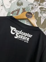 Remera negra de algodón con estampado de estilo anime con los personajes Touya y Yukito de Sakura Card Captor. Incluye el texto 'makosh' en la parte superior.
