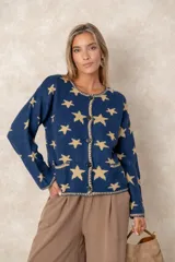 Saco abotonado de punto con diseño de estrellas en contraste, cuello redondo, mangas largas y dos bolsillos frontales. Presenta bordes con terminación enrollada.
