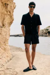 Short de baño de corte clásico, color negro, con cintura elástica ajustable mediante cordón, bolsillos laterales y bolsillo trasero con cierre autoadherente. Incluye suspensor interior de malla.