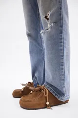 Zueco de cuero vacuno color marrón, con diseño de puntera reforzada y cordones decorativos con cuentas de madera en el empeine.