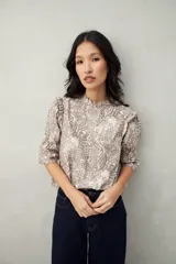 Blusa color beige con estampado abstracto en blanco, corte relajado, mangas 3/4 fruncidas y cuello con volados.