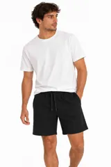 Short de felpa color negro, de corte relajado, con cintura elástica ajustable mediante cordón y bolsillos laterales.
