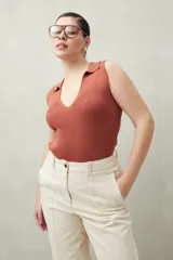 Top tejido color ladrillo, sin mangas, con escote en V y cuello tipo solapa. Tejido acanalado ajustado al cuerpo.