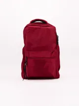 Mochila de diseño clásico en color bordó, con compartimento principal amplio y bolsillo frontal con cierre. Cuenta con manija superior reforzada y tiradores de cierre con detalle de cordón.