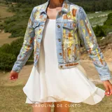 Campera de jean clara con diseño artístico pintado a mano en tonos amarillo y cobre, de manga larga y cierre frontal con botones metálicos.