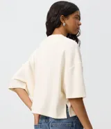Remera de modal color crudo, con diseño minimalista, calce amplio, cuello redondo y mangas cortas amplias con hombros caídos.