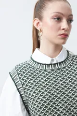 Chaleco tejido de algodón y acrílico, color rojo y blanco con patrón geométrico. Tiene cuello redondo y bordes acanalados en rojo.