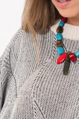 Buzo tejido de punto bicolor en tonos crudo y gris, con silueta relajada, mangas amplias con jaretas regulables en los puños y cuello redondo.