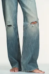 Jeans de tiro bajo y cinco bolsillos, de pierna ancha y larga. Cuenta con cierre frontal con cremallera y botón metálico.