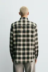Camisa de corte relaxed fit confeccionada en una mezcla de lana y algodón. Presenta un diseño de cuadros, cuello solapa, manga larga con puños abotonados y cierre frontal con botones.