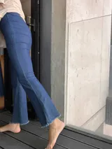 Calza de jean azul elastizada, tiro alto, corte ajustado y terminación desflecada en el ruedo.