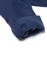 Camisa de manga larga Caterpillar de color azul, confeccionada en mezcla de tencel y algodón. Cuenta con cuello clásico, cierre frontal de botones, dos bolsillos en el pecho con solapa y botones, y diseño con mangas convertibles tipo roll-tab.