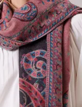 Bufandón rectangular de poliéster con estampado de arabescos en tonos rojos, azules y negros. Presenta terminaciones con flecos en los extremos.