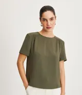 Blusa de poliéster color verde oliva, con cuello redondo, manga corta y detalle de pliegues fruncidos en la costura de los hombros.