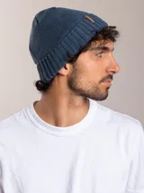 Gorro de lana azul con etiqueta de cuero sintético con logo de la marca en el frente.