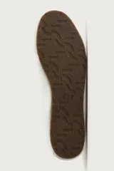 Zapatillas de cuero color blanco roto, de diseño minimalista con cordones, suela fina de goma marrón y detalles de gamuza en la puntera y los ojales.