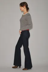 Jean de corte recto y tiro medio, confeccionado en denim azul oscuro de acabado raw. Presenta un diseño clásico de cinco bolsillos con costuras reforzadas y cierre frontal con botón y cremallera.
