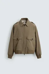 Cazadora de corte cropped fit, color verde oliva, confeccionada en mezcla de viscosa y algodón. Presenta cuello subido, manga larga, trabillas en los hombros, bolsillos de plastrón con solapa en la cadera y cierre frontal con cremallera.