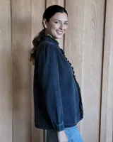 Camisa de jean azul con cuello alto con volados y volados en el frente.