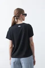 Remera negra de manga corta con estampado botánico en azul y la frase "NOTHING GROWS IN COMFORT".