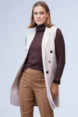 Chaleco largo tejido color blanco de la marca Sioni, con cuello solapa, doble botonadura dorada en el frente y bolsillos aplicados.