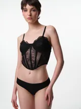 Corset de encaje negro con copa preformada, aros y ballenas estructurales. Presenta breteles elásticos ajustables y espalda cerrada.