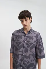 Camisa oversize de manga corta con cuello clásico y estampado abstracto en tonos grises.