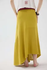 Falda larga de punto color mostaza, con cortes asimétricos, distintos puntos texturizados, ruedo irregular y pretina elástica con detalles en tono contrastante.
