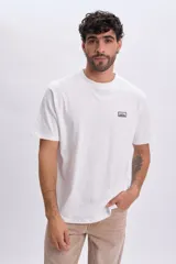 Remera manga corta de color blanco, confeccionada en algodón, con cuello redondo y una pequeña estampa rectangular en el pecho con la inscripción "Est.1990".
