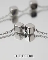 Collar de cadena fina de acero con pequeños dijes en forma de cubo distribuidos a lo largo de la pieza.