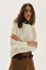 Sweater de punto color beige, con cuello redondo, manga larga y puños acanalados.