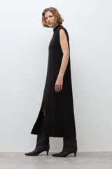 Vestido midi de tejido de punto, color negro, sin mangas, con cuello alto y tajo frontal en la falda.